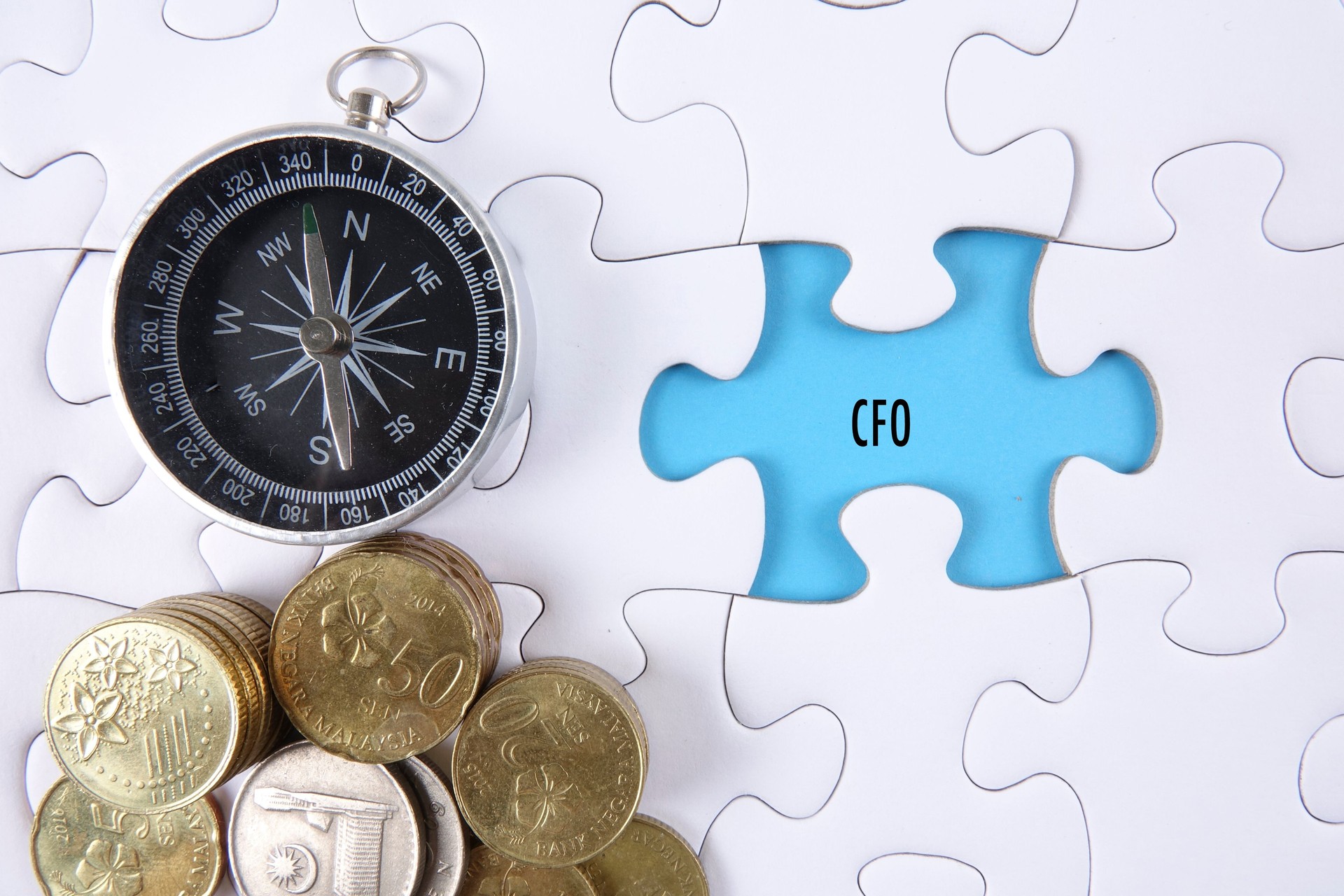Close-Up Of Compass And Coins On Jigsaw Puzzle With Text